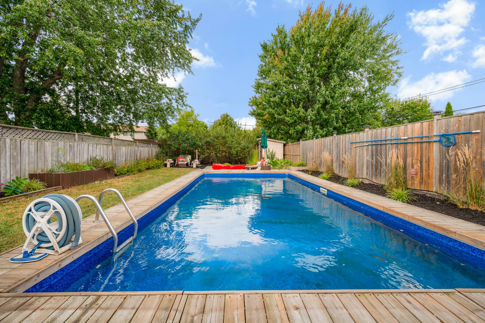 The 16 by 32 foot in-ground pool with wood decking and a fenced yard